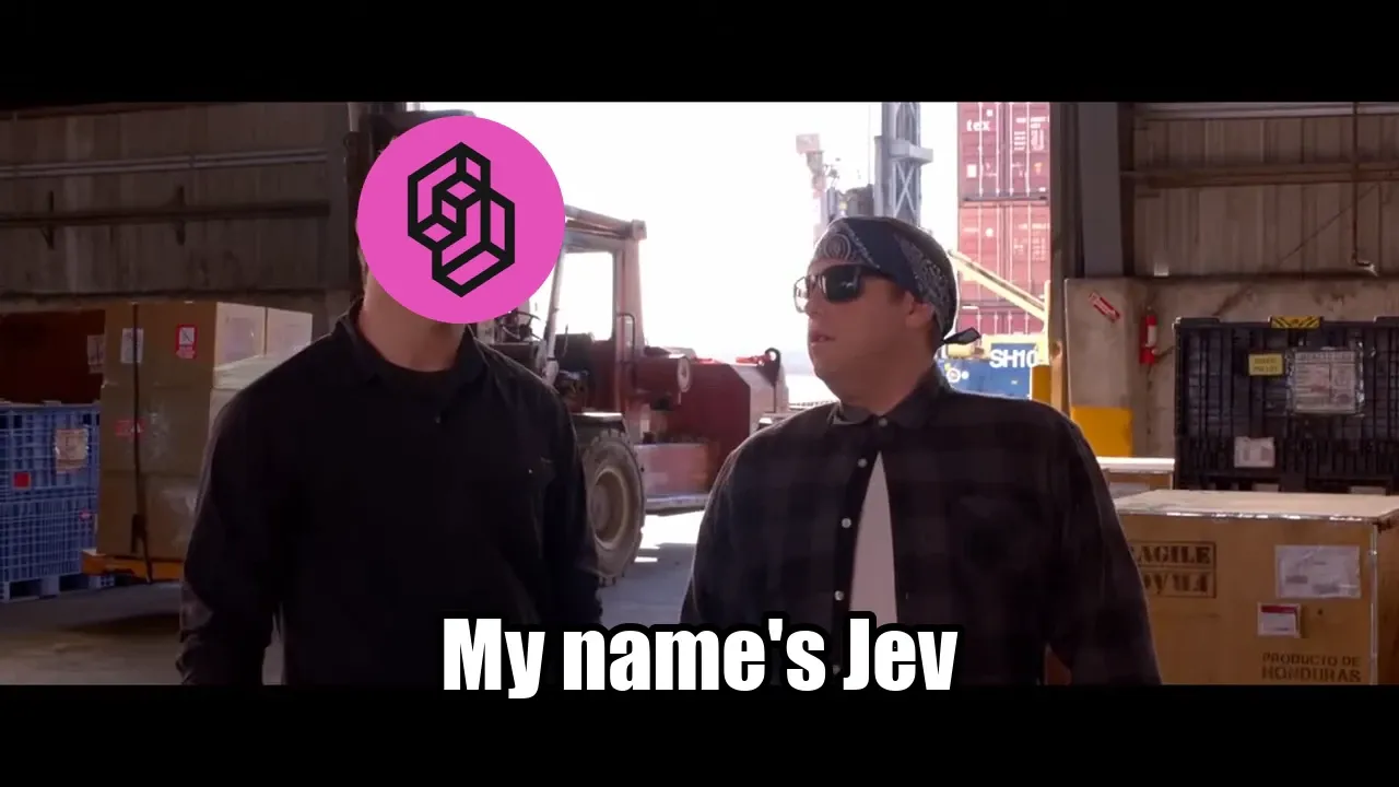 The “My name is Jeff” scene from 22 Jump Street: Schmidt and Jenko walk through a warehouse of crates, Jenko's face covered by a pink logo; Schmidt, in a bandana and sunglasses, turns to him as the subtitle reads “My name's Jev.”